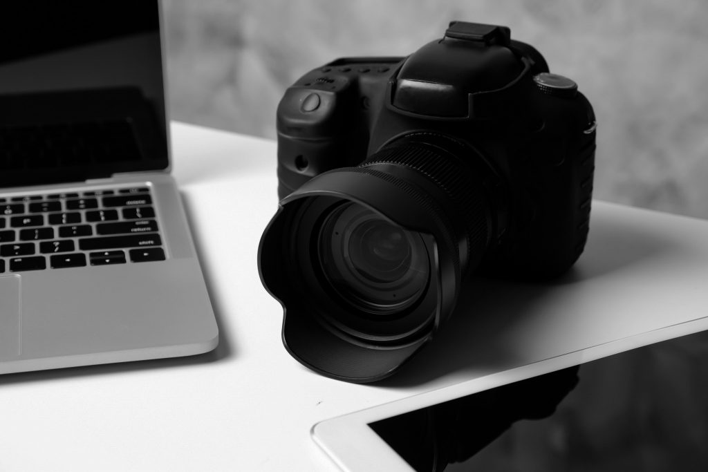 SChwarze Kamera auf dem tisch neben Laptop und Tablet